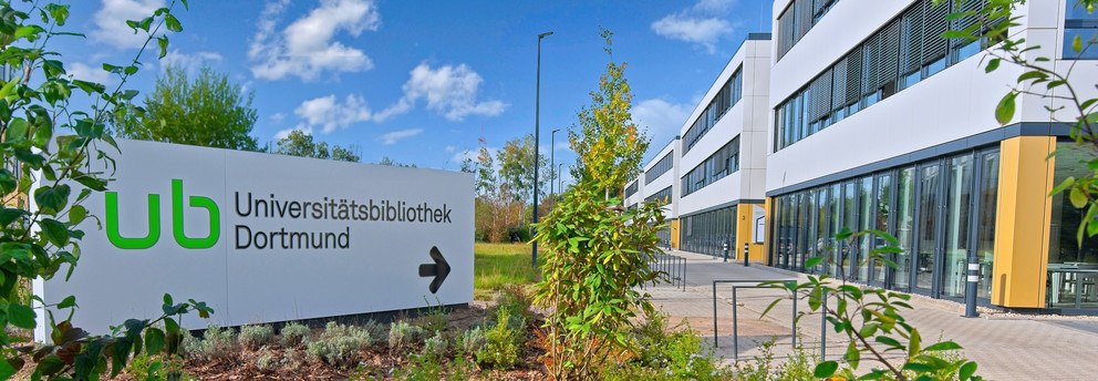 Wegweiser Sebrath-Bibliothek Großes weißes Schild mit Pfeil weist zum Gebäude Sebrathweg 7