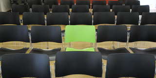 A green chair in the middle of black chairs