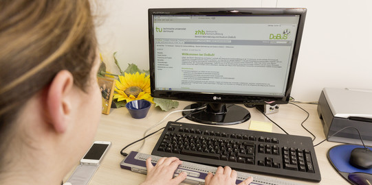Eine blinde Studentin sitzt an einem PC und lernt mit der ALVA Tastatur.