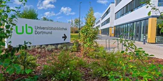 Wegweiser Sebrath-Bibliothek Großes weißes Schild mit Pfeil weist zum Gebäude Sebrathweg 7
