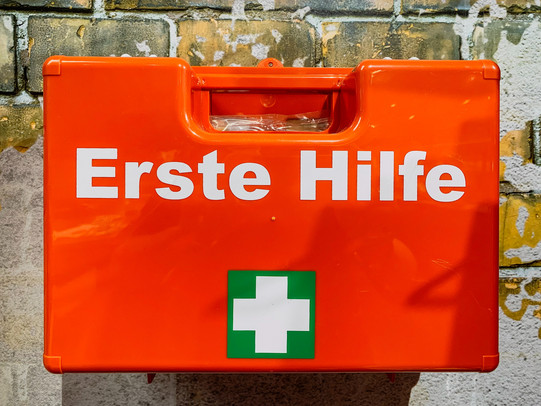 Erste-Hilfe-Koffer Orangefarbiger Erste-Hilfe-Koffer hängt an einer Wand