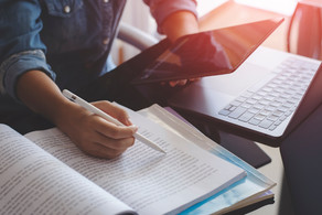 Frau mit Tablet, Laptop, Büchern Junge Frau mit einem Stift in der Hand arbeitet mit einem Tablet, einem Laptop und Büchern