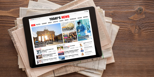 Tablet mit Nachrichten-Website auf Zeitungsstapel Ein Tablet mit einer News-Seite liegt auf einem Zeitungsstapel