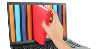 Laptop und Bücher Laptop mit bunten Büchern, von denen eins herausgezogen wird