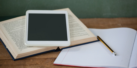 Tablet, Heft und Buch auf einem Tisch Ein Tablet, ein Buch und ein Heft liegen auf einem Tisch